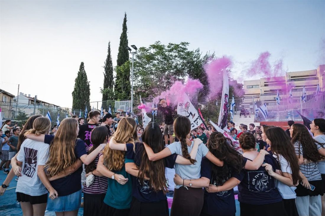 חניכות וחניכים בשבט גוננים מחובקים במורל עם עשן ורוד ודגלים