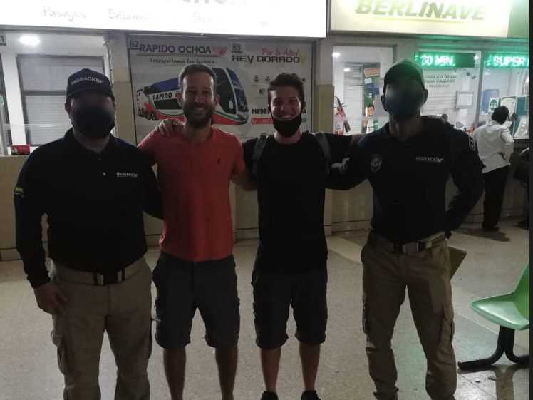 שבי וחבר מצטלמים עם שני פקחי הגירה בתחנת אוטובוסים בקולומביה